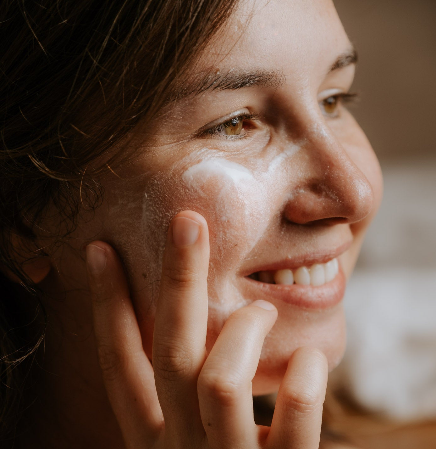 Woman applying cream to her face with a blurred background