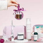 a christmas beauty bauble behind held over skincare products