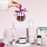 a christmas beauty bauble behind held over skincare products