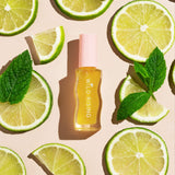 Skincare bottle labeled 'Wild Rising' surrounded by lime slices and mint leaves on a beige background