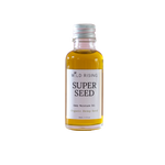 A small glass bottle of Wild Rising Super Seed Deep Moisture Oil filled with golden-yellow oil, featuring a white label and a silver metal cap, set against a plain white background.