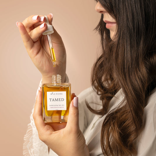 Tamed Conditioning Hair Oil with model holding dropper