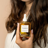 wild rising hair oil tamed being held by a model