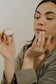 wild rising skincare model applying lip balm