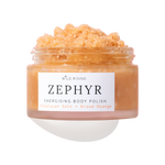 A clear jar of Wild Rising Zephyr Energising Body Polish filled with a peachy-orange granular scrub, shown on a white background with a soft shadow.
