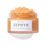 A clear jar of Wild Rising Zephyr Energising Body Polish filled with a peachy-orange granular scrub, shown on a white background with a soft shadow.