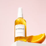 sundaze coconut and orange body oil on a ledge