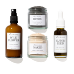 Four skincare products from Wild Rising arranged on a white background: a brown spray bottle labeled Wild Flower, a gray detox mask jar labeled Detox, a beige powder cleanser jar labeled Naked, and a dark seed oil bottle labeled Super Seed.