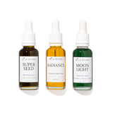 Three Wild Rising dropper bottles arranged side by side on a white background: Super Seed deep moisture oil in dark amber, Radiance restorative beauty serum in golden amber, and Moon Light smoothing serum in green.