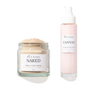Two skincare products from Wild Rising on a white background: a clear glass jar of Naked Powder to Foam Cleaner with beige powder, and a pale pink pump bottle of Canvas Cream Cleaner.