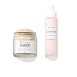 Two skincare products from Wild Rising on a white background: a clear glass jar of Naked Powder to Foam Cleaner with beige powder, and a pale pink pump bottle of Canvas Cream Cleaner.
