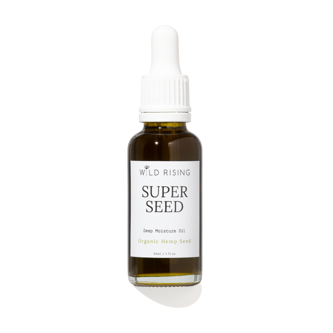 A 30ml glass dropper bottle of Wild Rising Super Seed Deep Moisture Oil, featuring an amber-colored bottle, a white dropper cap, and a white label with black text.