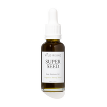 A 30ml glass dropper bottle of Wild Rising Super Seed Deep Moisture Oil, featuring an amber-colored bottle, a white dropper cap, and a white label with black text.
