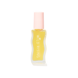 A small clear bottle filled with pale yellow liquid, featuring a light pink cap and vertical white text reading 'WILD RISING' on the front, centered on a plain white background.