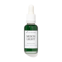 A bottle of Wild Rising Moon Light Smoothing Serum with a white dropper cap and a white label, containing a dark green liquid, set against a plain white background with a soft shadow.