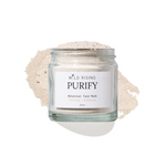 A clear glass jar labeled 'WILD RISING PURIFY Botanical Face Mask' filled with a light beige powder, set against a white background with a matching powder spill behind it.