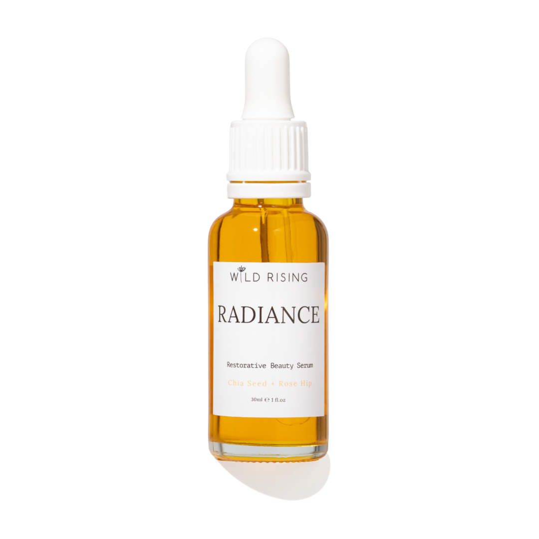 A 30ml glass dropper bottle of Wild Rising Radiance Retinolative Beauty Serum, filled with golden-yellow oil, featuring a white label and white dropper cap, set against a plain white background with a soft shadow.