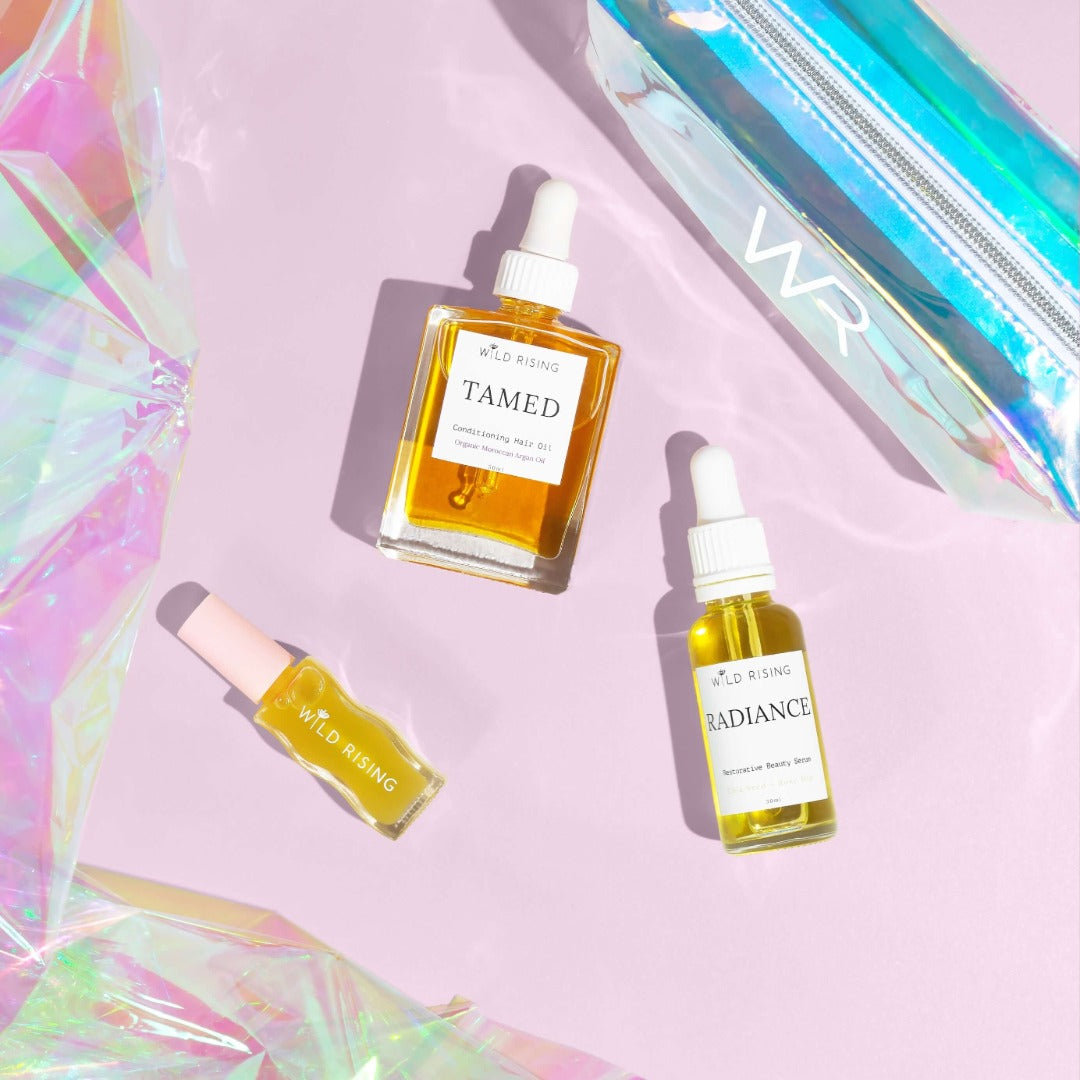hair oil, lip oil and face oil laid flat with holographic bag