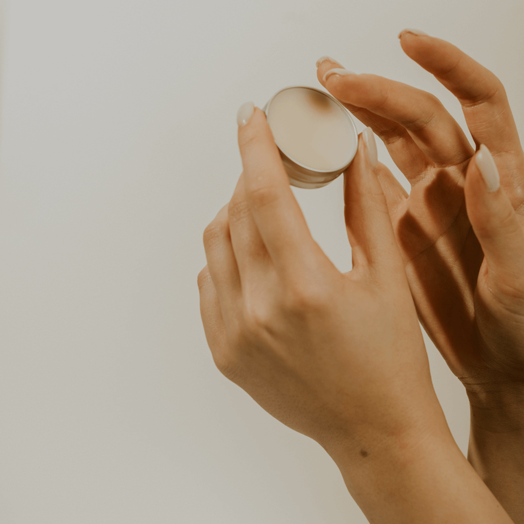 two hands holding an opened lip balm tin