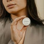 model with brown hair holding a lip balm