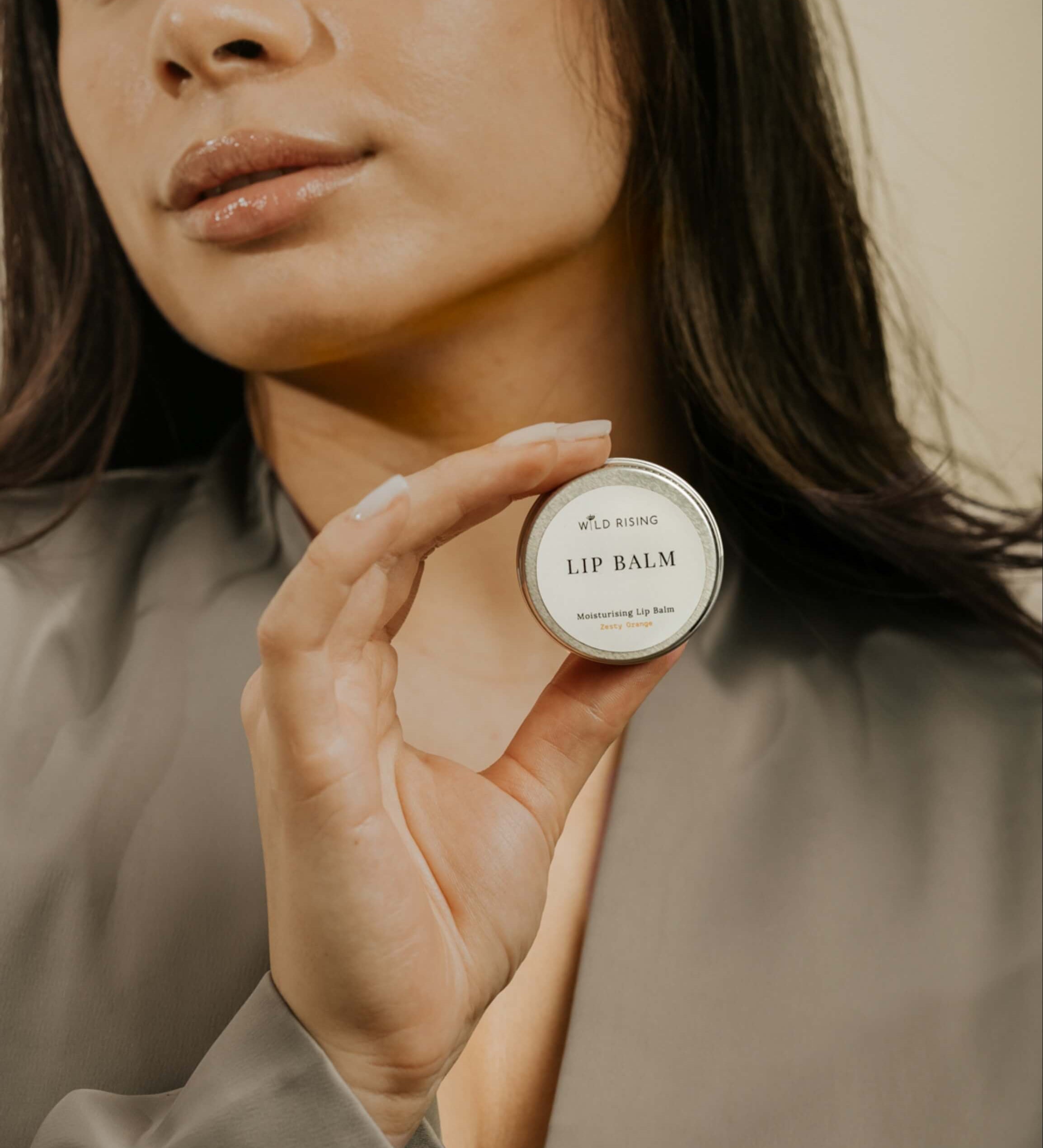 model with brown hair holding a lip balm