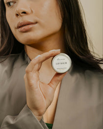 model with brown hair holding a lip balm