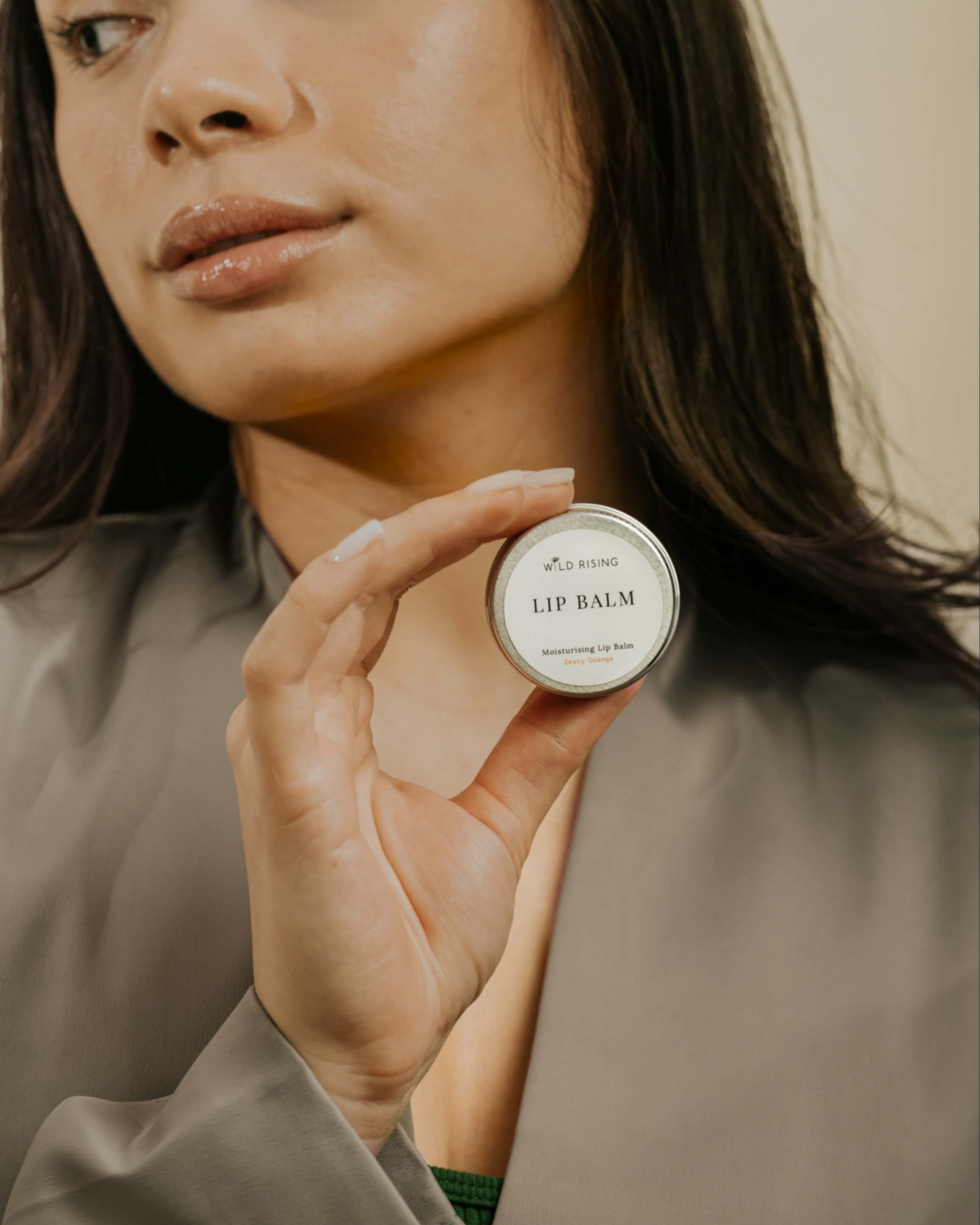 model with brown hair holding a lip balm
