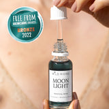 Hand holding a bottle of 'Moon Light' serum with a dropper, against a neutral background.