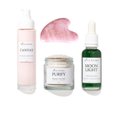 Four skincare products from Wild Rising arranged on a white background: a pale pink pump bottle labeled Canvas, a pink gua sha massage tool, a clear jar labeled Purify Botanical Face Mask, and a dark green dropper bottle labeled Moon Light Smoothing Serum