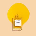 square glass bottle aid down with orange hair oil spilling out