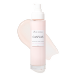 A bottle of Wild Rising Canvas Moisturizing Cream Cleanser with a white pump dispenser, set against a clean white background with a pale pink cream smear behind it.