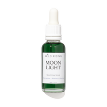A bottle of Wild Rising Moon Light Smoothing Serum with a white dropper cap and a white label, containing a dark green liquid, set against a plain white background with a soft shadow.