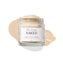A clear glass jar labeled 'WILD RISING NAKED' containing a light beige powder, set against a white background with a matching beige powder smear behind it.