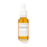 A 30ml glass dropper bottle of Wild Rising Radiance  Beauty Serum, filled with golden-yellow oil, featuring a white label and white dropper cap on a white background.