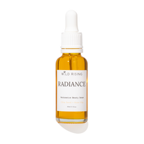 A 30ml glass dropper bottle of Wild Rising Radiance  Beauty Serum, filled with golden-yellow oil, featuring a white label and white dropper cap on a white background.