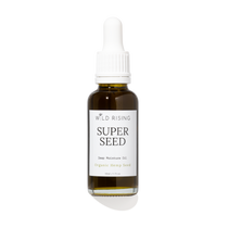 A 30ml glass dropper bottle of Wild Rising Super Seed Deep Moisture Oil, featuring an amber-colored bottle, a white dropper cap, and a white label with black text.