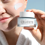 Person applying cream to face with Celeste jar in hand against a clear sky.
