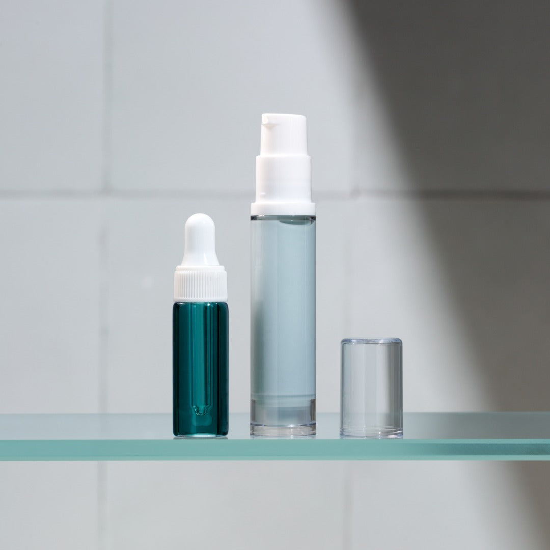 Two skincare bottles on a glass shelf with a neutral background