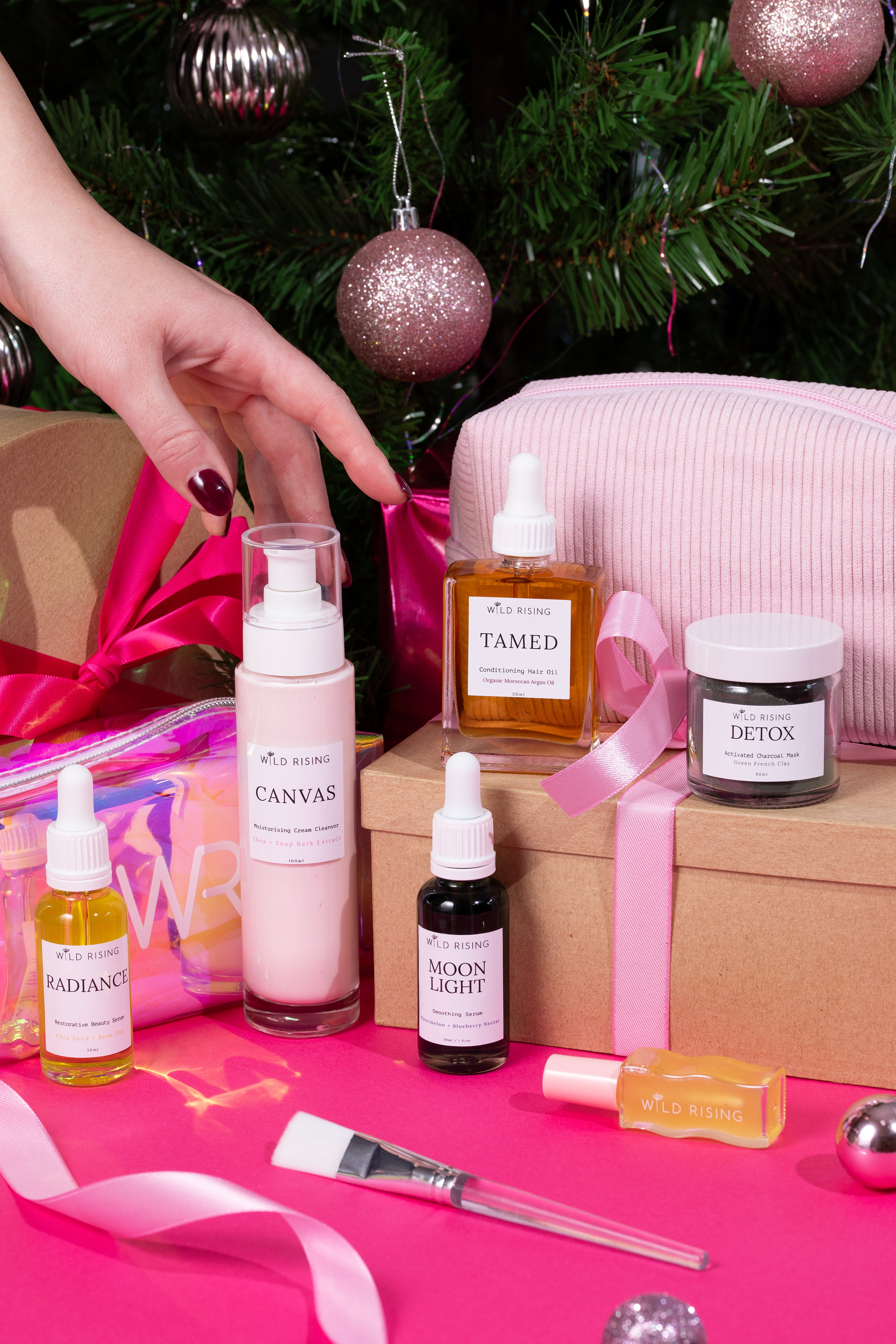 Cosmetic products on a pink surface with a Christmas tree in the background