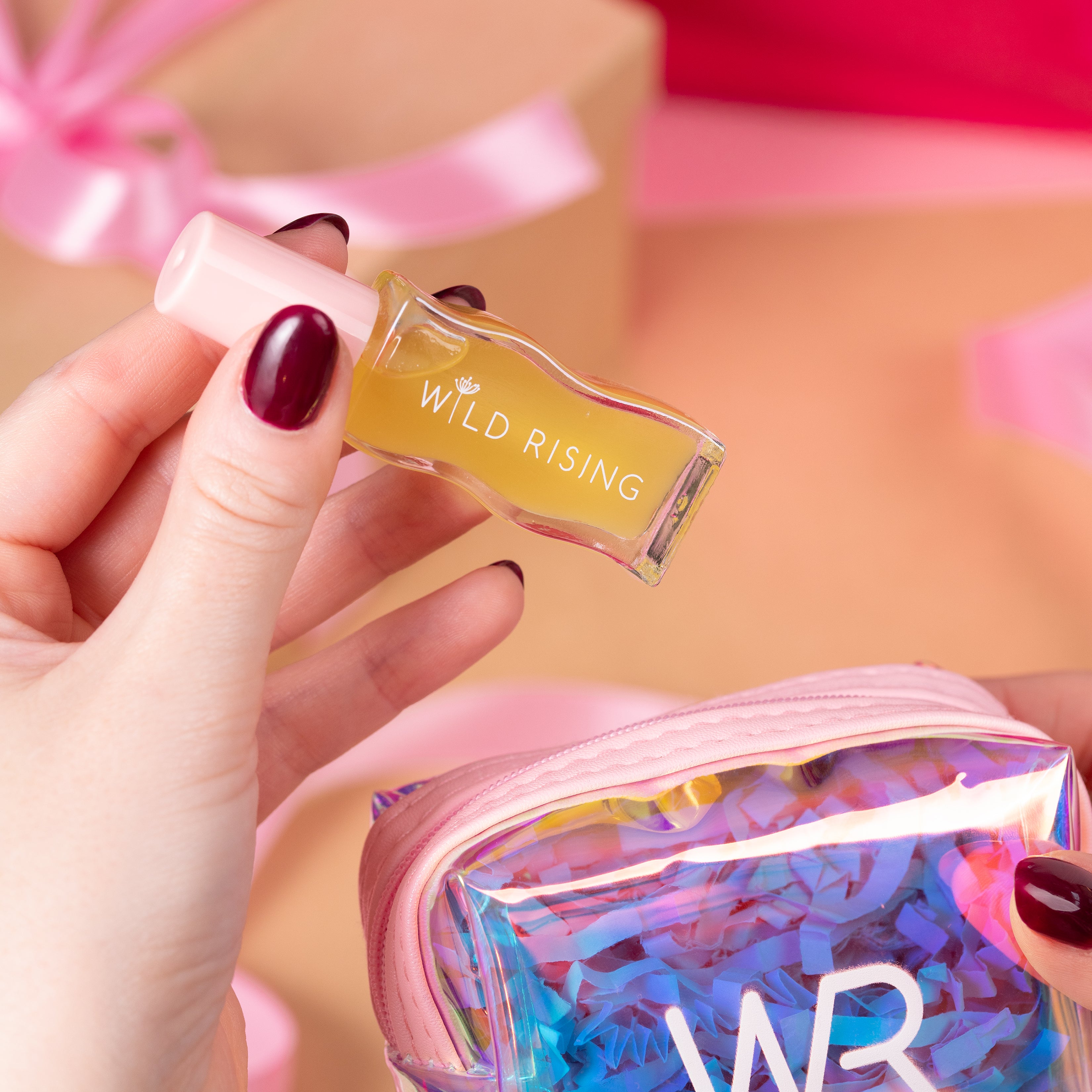 Hand holding a small rectangular product labeled 'Wild Rising' with a colorful 'WR' pouch in the background.