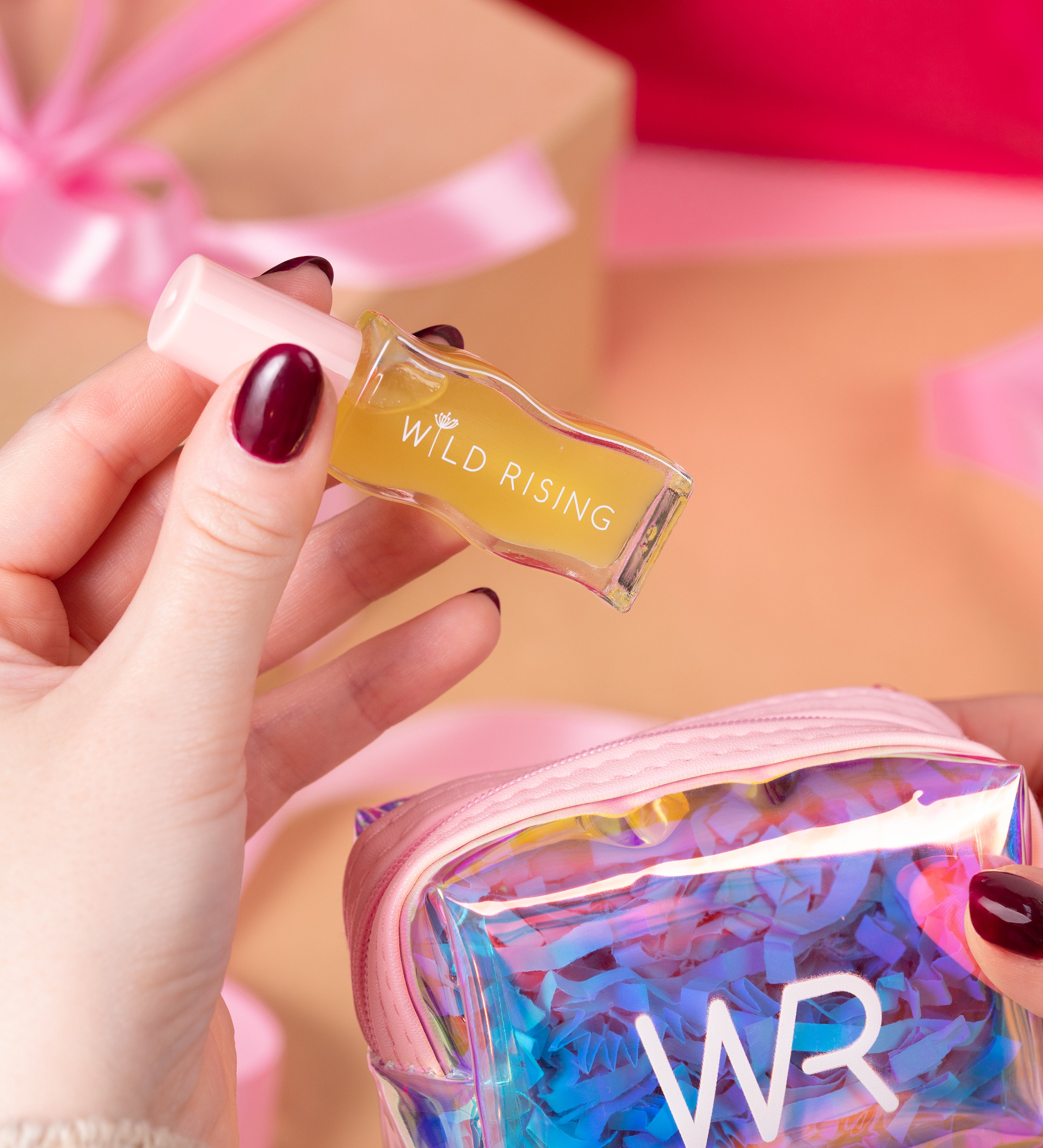 Hand holding a small rectangular product labeled 'Wild Rising' with a colorful 'WR' pouch in the background.