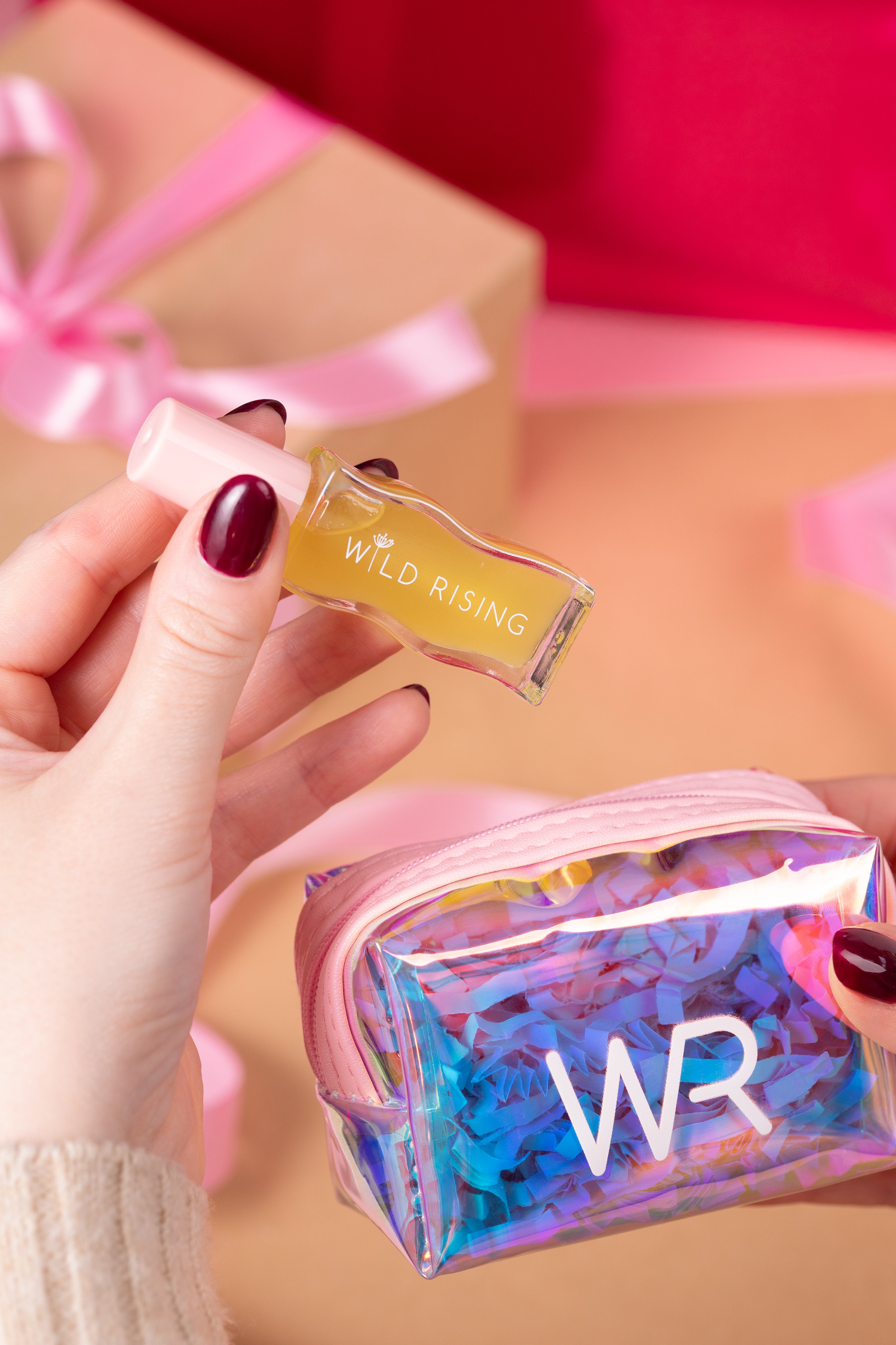 Hand holding a small rectangular product labeled 'Wild Rising' with a colorful 'WR' pouch in the background.