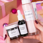 Hand holding skincare products with visible brand names against a colorful background