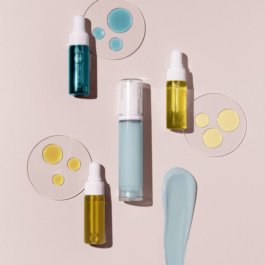 Skincare products including bottles and droppers on a light pink background