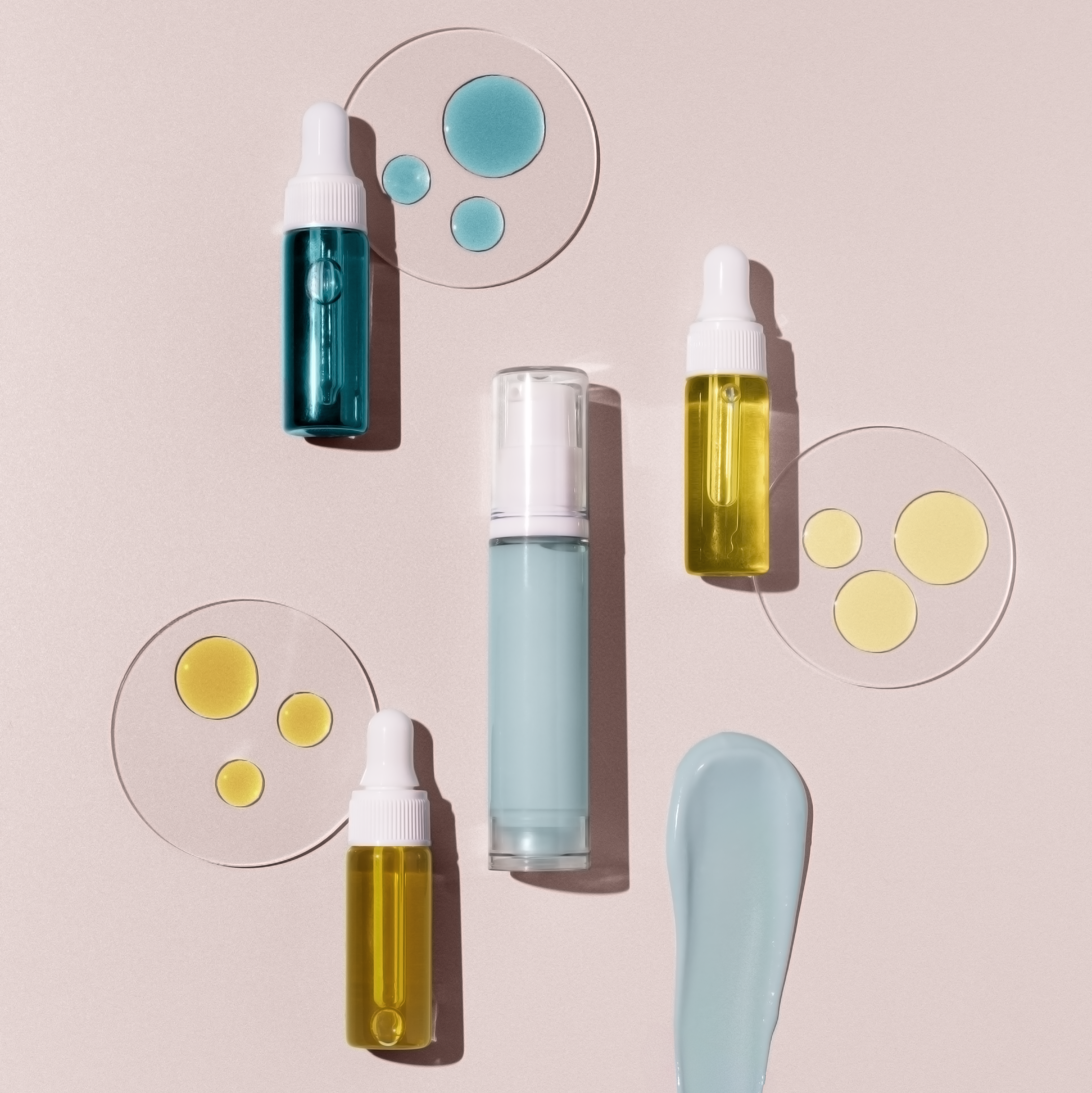 Skincare products including bottles and droppers on a light pink background