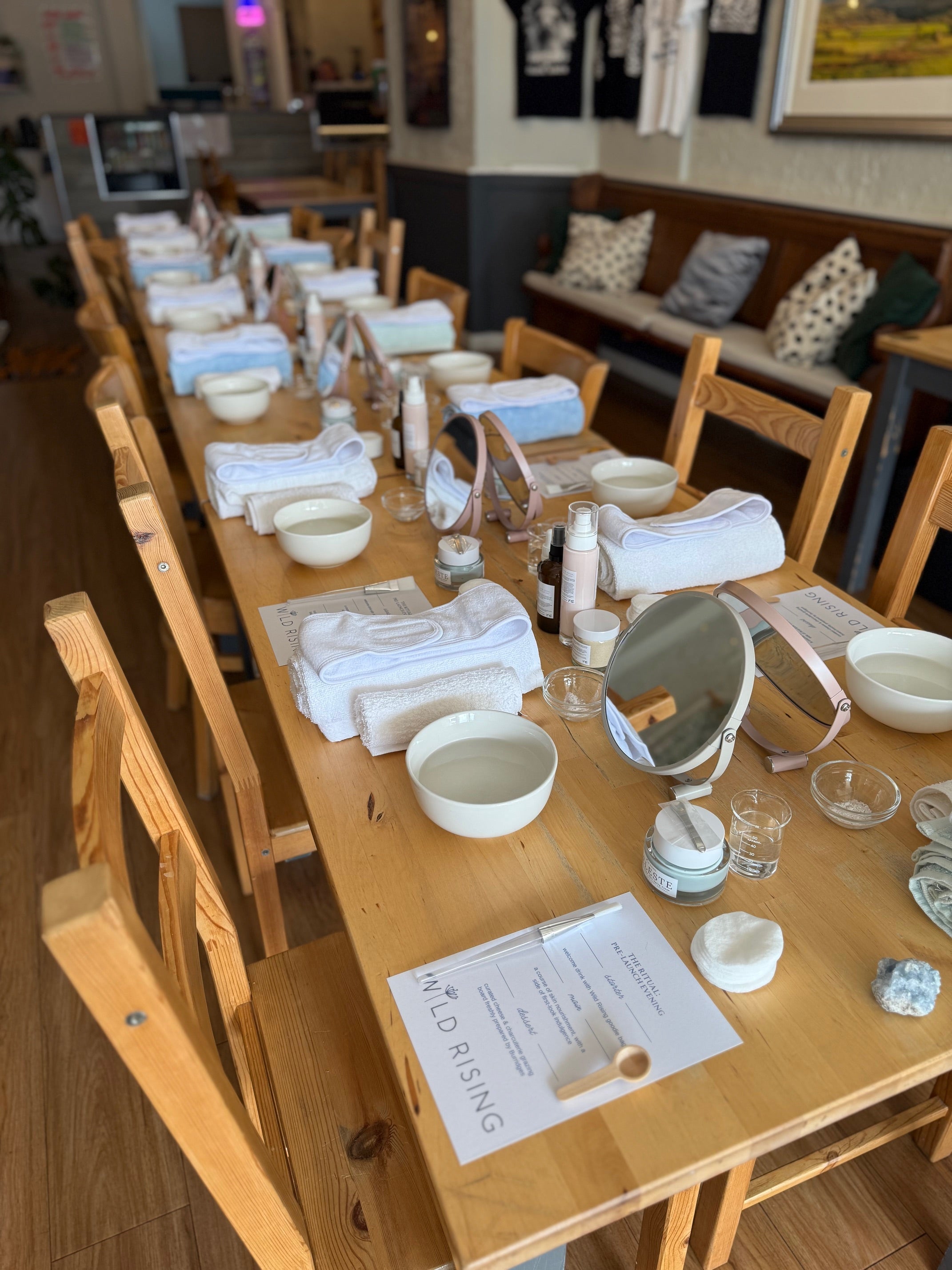 Long wooden table set with ceramic items and a certificate in a room with wooden chairs and a couch.