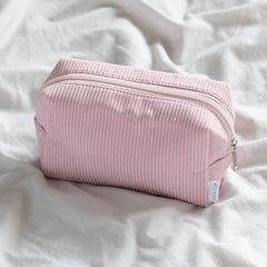 pink cosmetic bag on bed with zipper