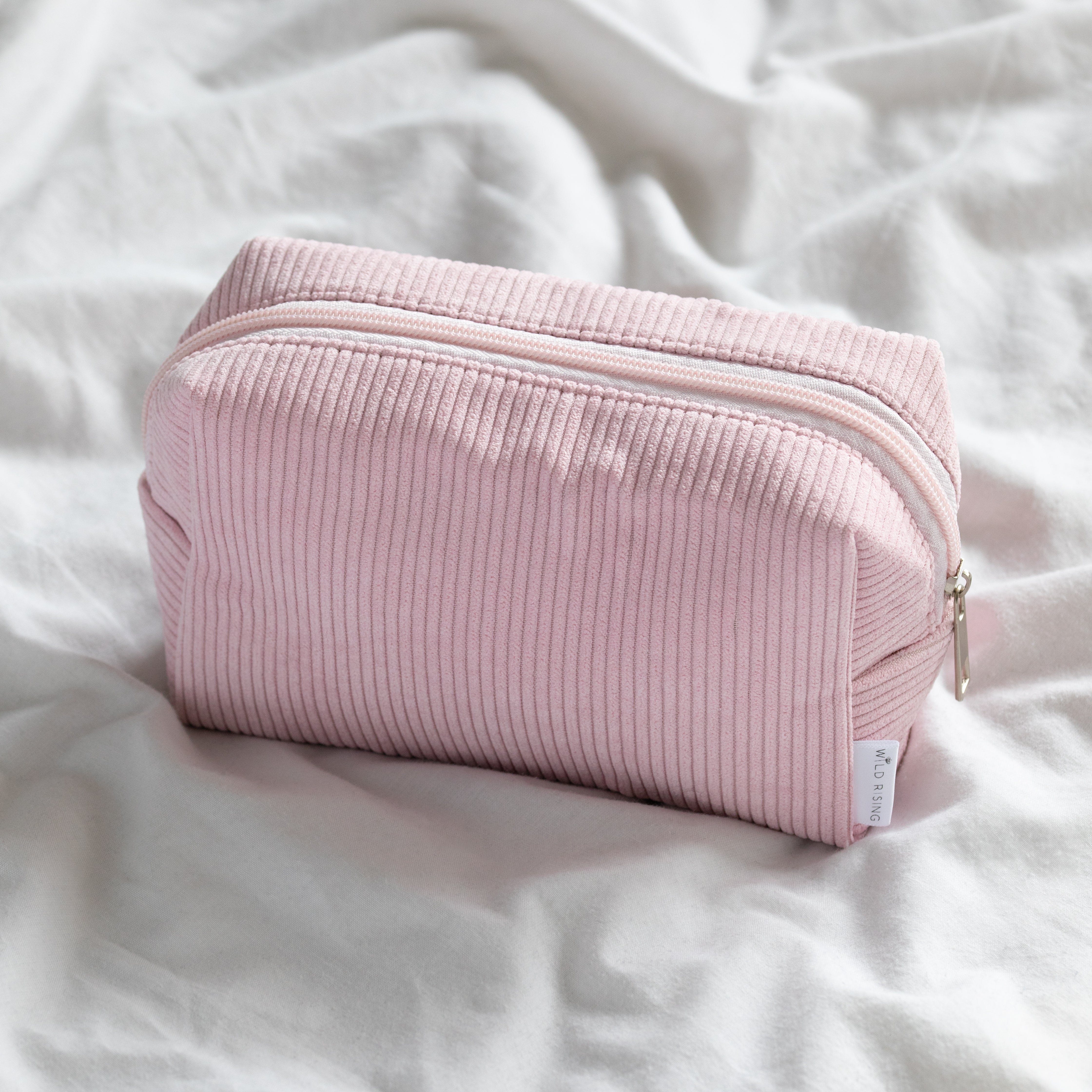 pink cosmetic bag on bed with zipper