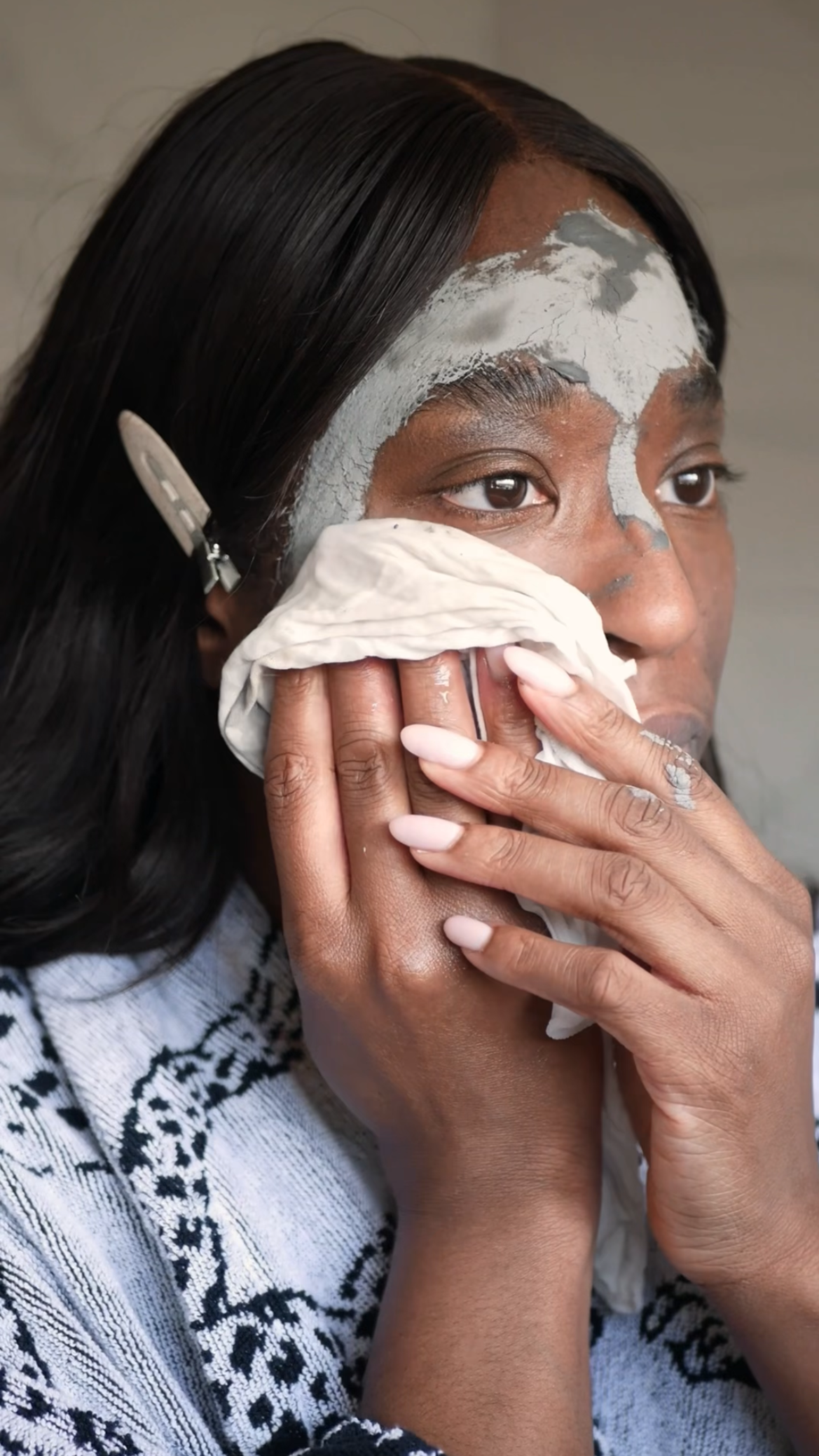 Person applying a facial mask with a towel