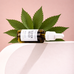 hemp seed face oil laid flat with hemp leaves around it